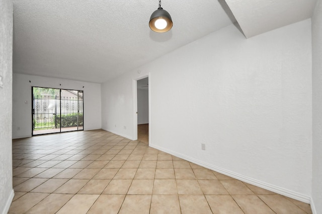 tiled empty room featuring a textured ceiling