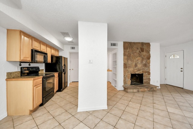 kitchen featuring black appliances, light tile patterned floors, a fireplace, a textured ceiling, and light brown cabinetry