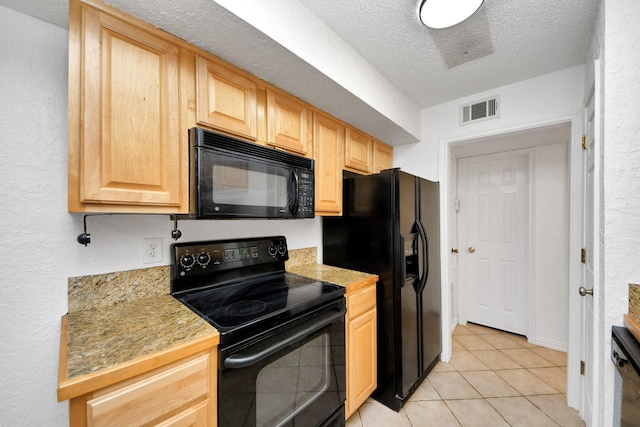 kitchen featuring light tile patterned flooring, light brown cabinetry, a textured ceiling, and black appliances