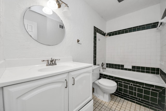 full bathroom featuring tile patterned flooring, vanity, toilet, and tiled shower / bath combo