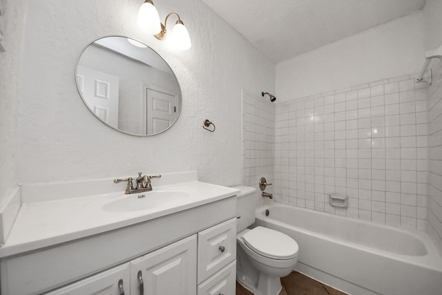 full bathroom featuring vanity, tiled shower / bath, tile patterned flooring, toilet, and a textured ceiling