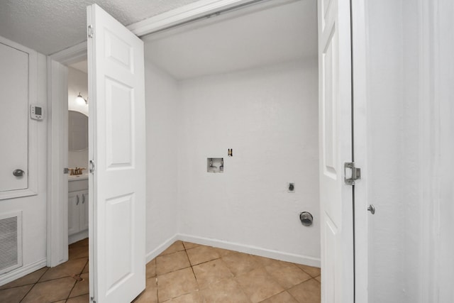 laundry room with hookup for a washing machine, a textured ceiling, light tile patterned floors, and electric dryer hookup