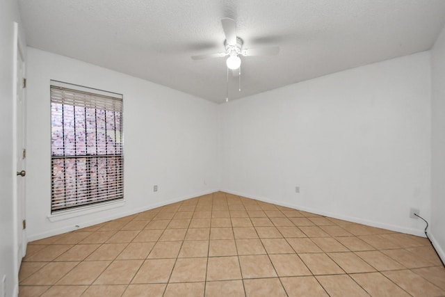 spare room with ceiling fan, light tile patterned flooring, and a textured ceiling