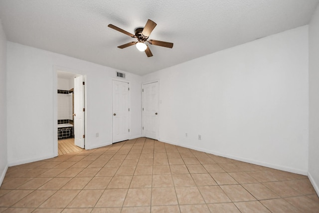 tiled spare room featuring ceiling fan and a textured ceiling