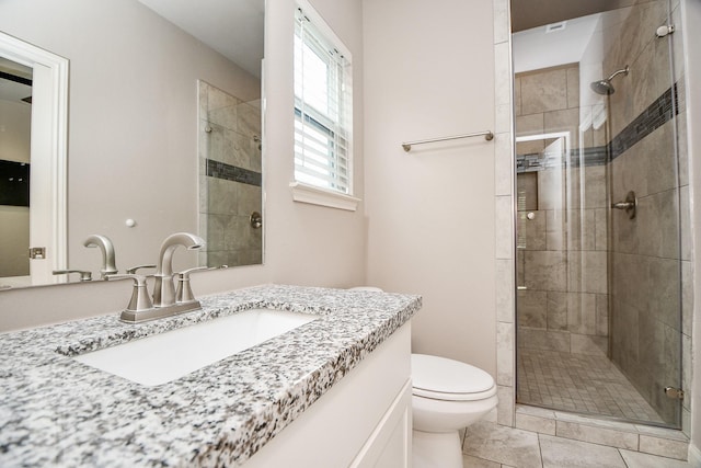 bathroom featuring tile patterned flooring, vanity, a shower with shower door, and toilet