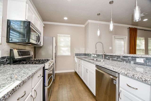 kitchen featuring white cabinetry, sink, light hardwood / wood-style flooring, appliances with stainless steel finishes, and ornamental molding