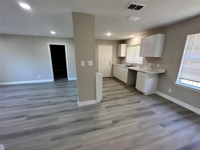 kitchen with white cabinets, light hardwood / wood-style flooring, a healthy amount of sunlight, and sink