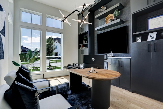 office space featuring built in shelves, light hardwood / wood-style flooring, and a notable chandelier