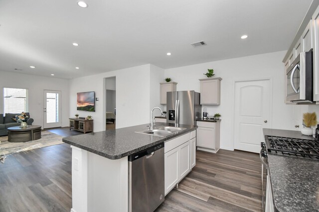 kitchen featuring dark wood-type flooring, a center island with sink, sink, white cabinetry, and stainless steel appliances