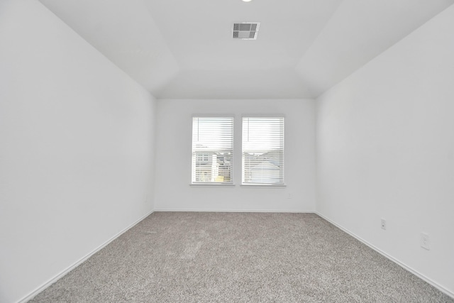 spare room featuring light colored carpet and vaulted ceiling