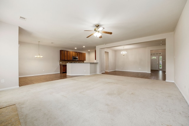 unfurnished living room featuring carpet and ceiling fan with notable chandelier