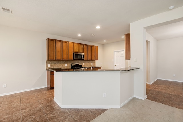 kitchen with kitchen peninsula, stainless steel appliances, light tile patterned floors, and tasteful backsplash