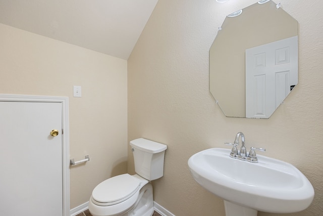 bathroom featuring toilet, lofted ceiling, and sink