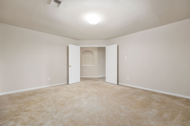 spare room with light colored carpet and a textured ceiling