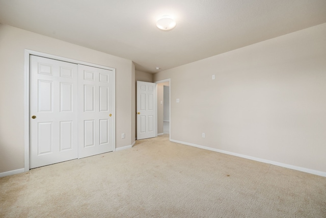 unfurnished bedroom with light colored carpet and a closet