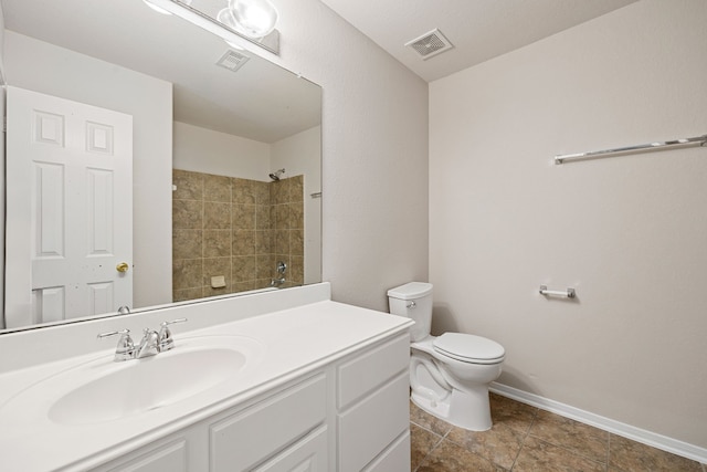 bathroom with a tile shower, vanity, and toilet