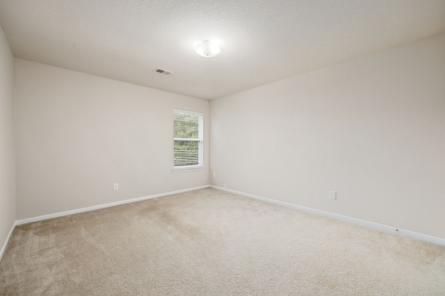 carpeted empty room featuring a textured ceiling