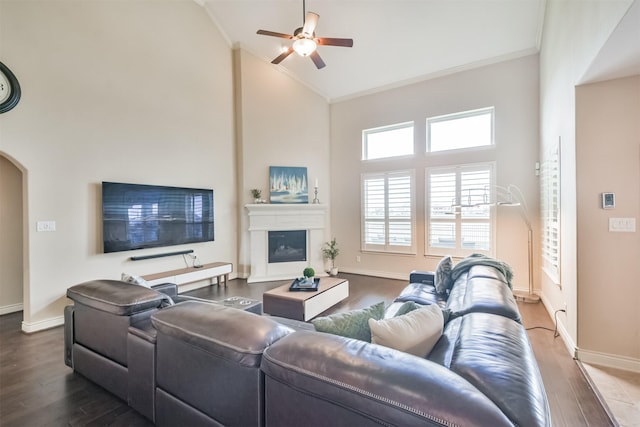 living room with ceiling fan, dark hardwood / wood-style flooring, crown molding, and high vaulted ceiling