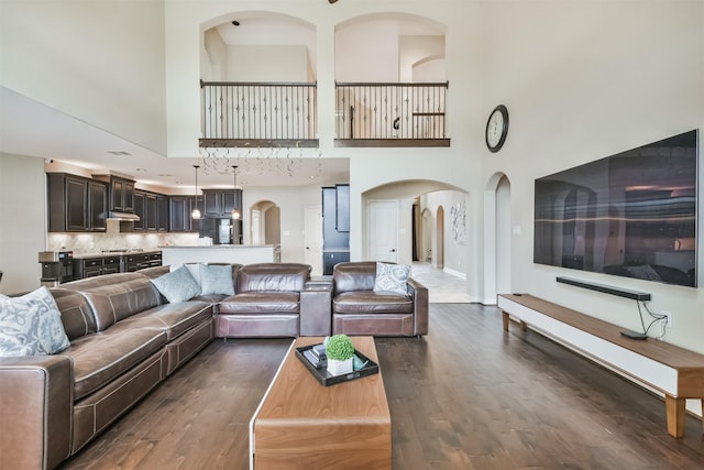 living room with dark hardwood / wood-style floors and a towering ceiling