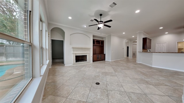 unfurnished living room featuring ceiling fan and ornamental molding