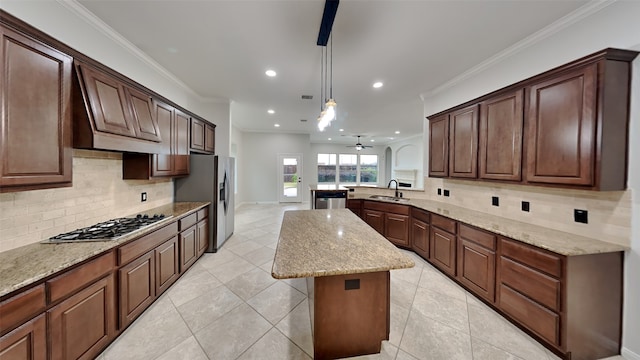 kitchen featuring ceiling fan, sink, crown molding, pendant lighting, and a kitchen island