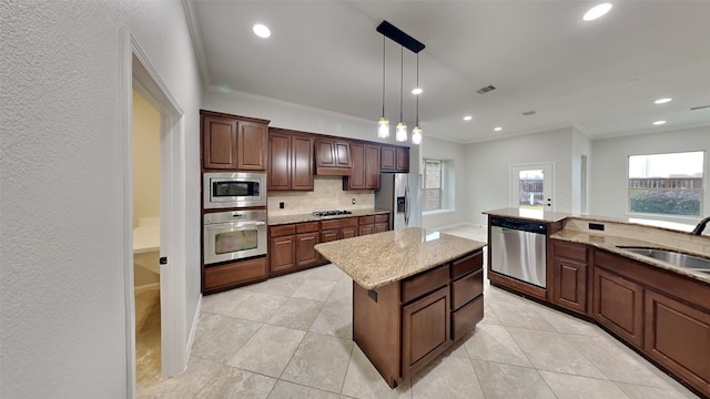 kitchen with appliances with stainless steel finishes, tasteful backsplash, sink, decorative light fixtures, and a kitchen island