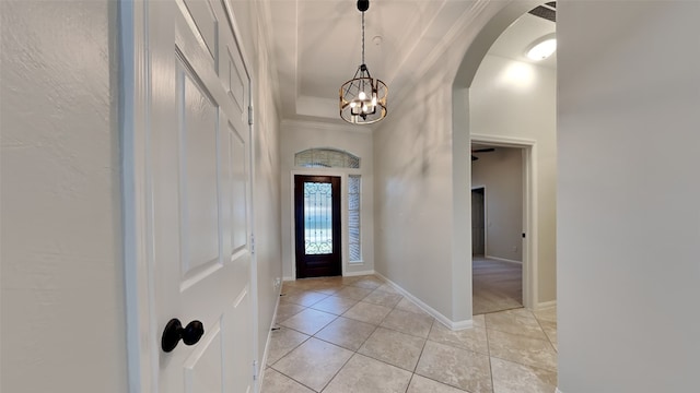 entryway with light tile patterned floors, an inviting chandelier, and crown molding