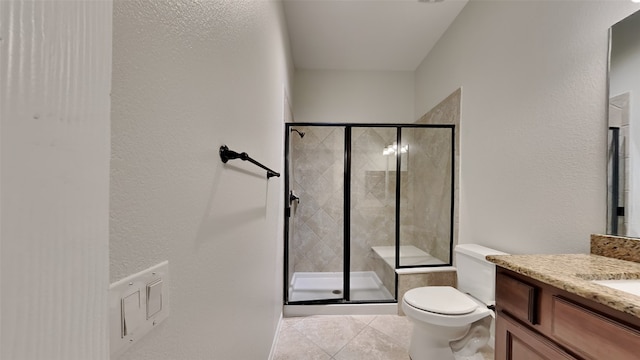 bathroom featuring tile patterned floors, vanity, a shower with shower door, and toilet