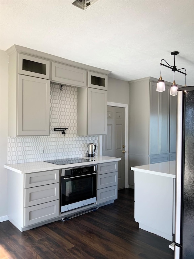 kitchen with dark hardwood / wood-style flooring, stainless steel fridge, black electric cooktop, oven, and gray cabinets