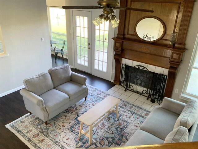 living room with french doors, light hardwood / wood-style floors, ceiling fan, and a tiled fireplace