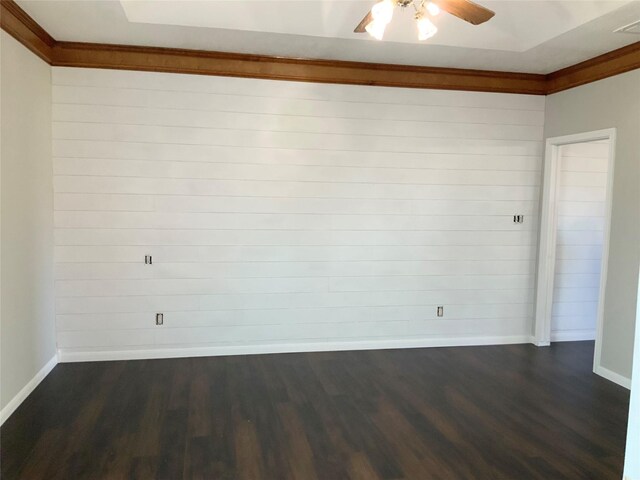 spare room featuring wooden walls, dark hardwood / wood-style floors, ceiling fan, and crown molding