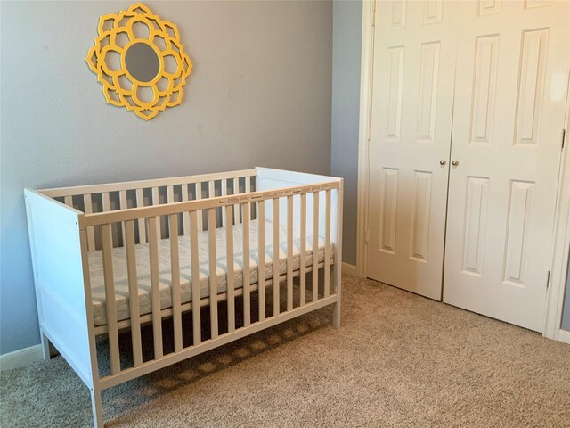 bedroom featuring carpet, a closet, and a nursery area