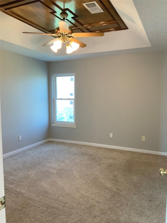 carpeted empty room featuring a raised ceiling and ceiling fan