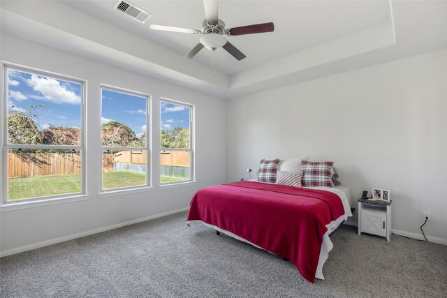 bedroom with a raised ceiling, ceiling fan, and carpet floors