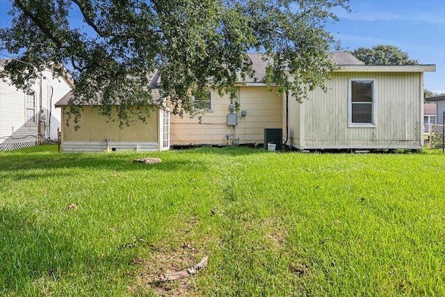 back of property with a lawn and central AC