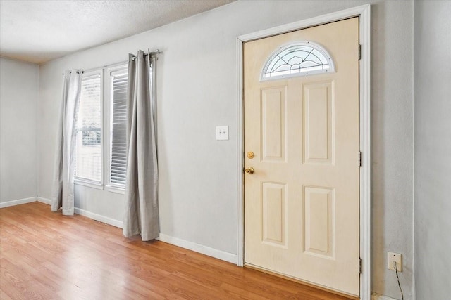 entrance foyer with wood-type flooring, a textured ceiling, and a wealth of natural light