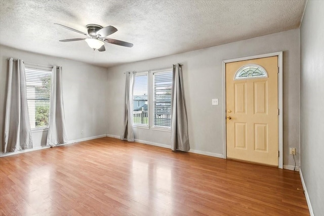 entryway with a wealth of natural light, light hardwood / wood-style flooring, and a textured ceiling