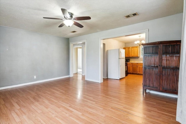 unfurnished living room with ceiling fan with notable chandelier, a textured ceiling, and light hardwood / wood-style floors