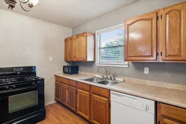 kitchen featuring black appliances, sink, light hardwood / wood-style flooring, a textured ceiling, and a notable chandelier