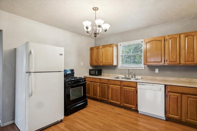 kitchen with sink, an inviting chandelier, light hardwood / wood-style floors, pendant lighting, and black appliances