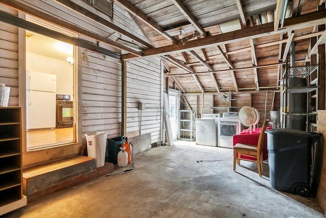 interior space with separate washer and dryer, wooden walls, and white fridge