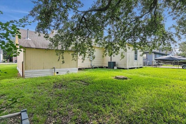 rear view of house with central air condition unit and a lawn