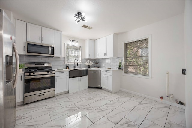 kitchen with decorative backsplash, white cabinetry, sink, and appliances with stainless steel finishes