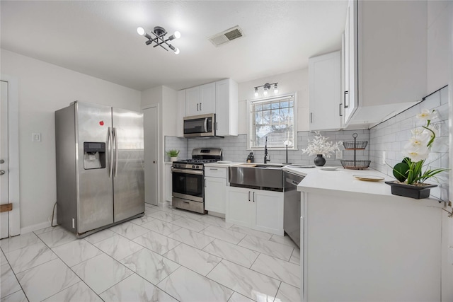 kitchen with white cabinets, decorative backsplash, and stainless steel appliances