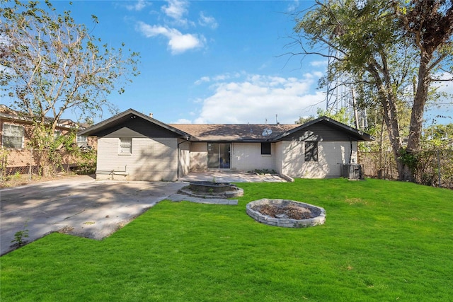 rear view of property with a lawn, a patio area, central AC unit, and an outdoor fire pit