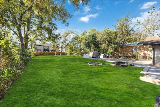 view of yard featuring a storage unit and an outdoor fire pit