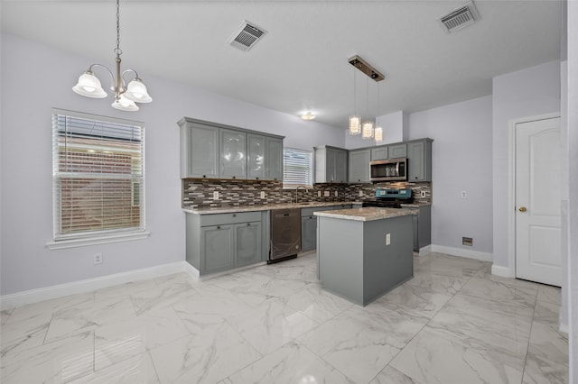 kitchen with hanging light fixtures, stainless steel appliances, an inviting chandelier, gray cabinets, and a kitchen island