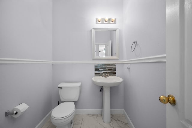 bathroom with decorative backsplash, toilet, and sink