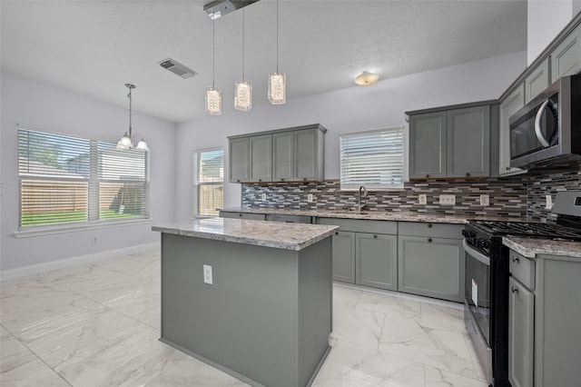 kitchen featuring gray cabinets, a kitchen island, appliances with stainless steel finishes, and pendant lighting