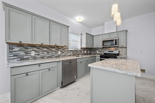 kitchen featuring appliances with stainless steel finishes, sink, a center island, gray cabinets, and hanging light fixtures